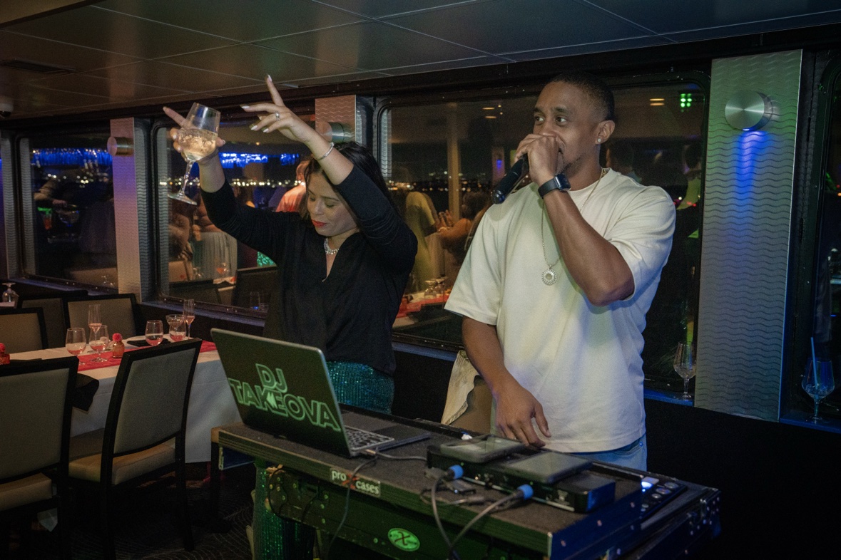 DJ Takeova on the microphone behind a yacht party DJ booth