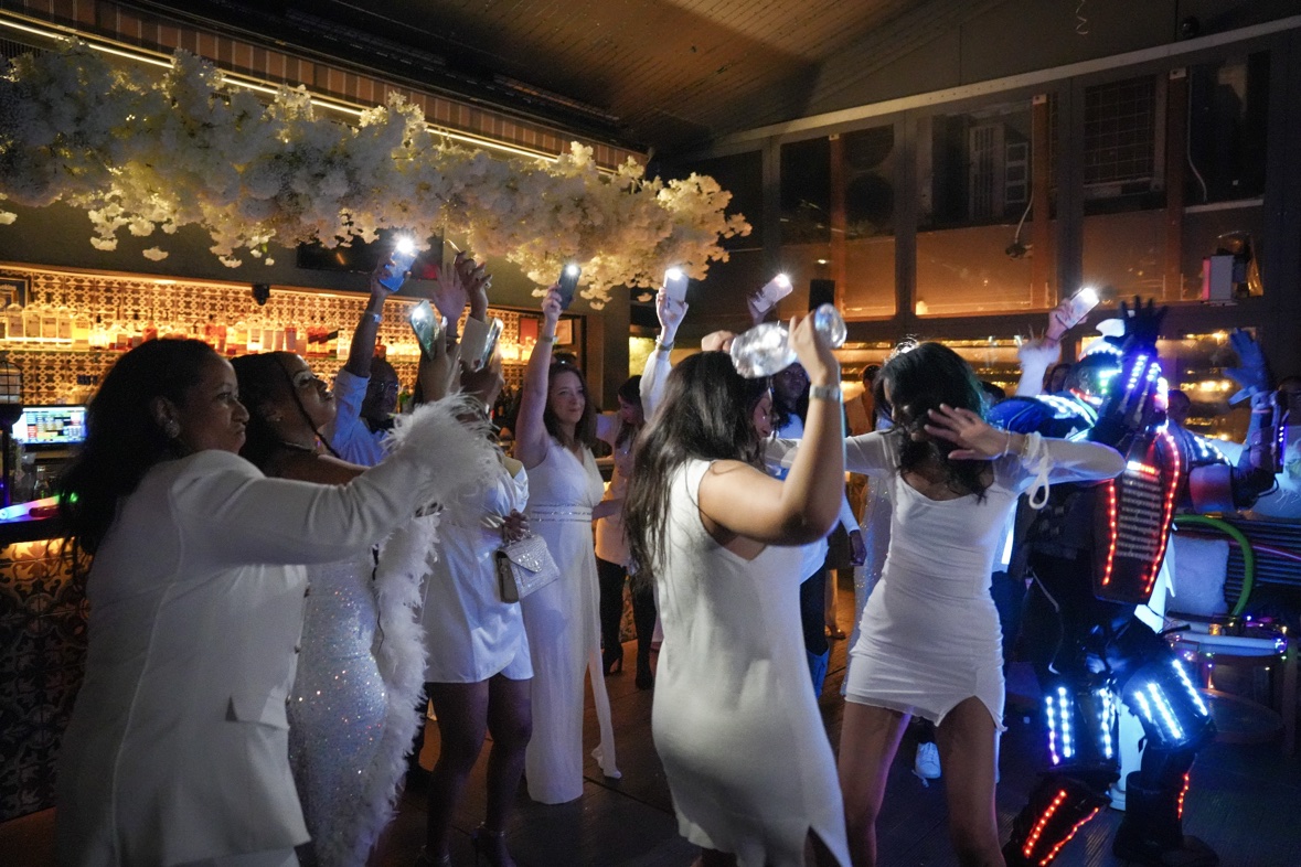 Guests in white dancing with raised phones at an all-white party